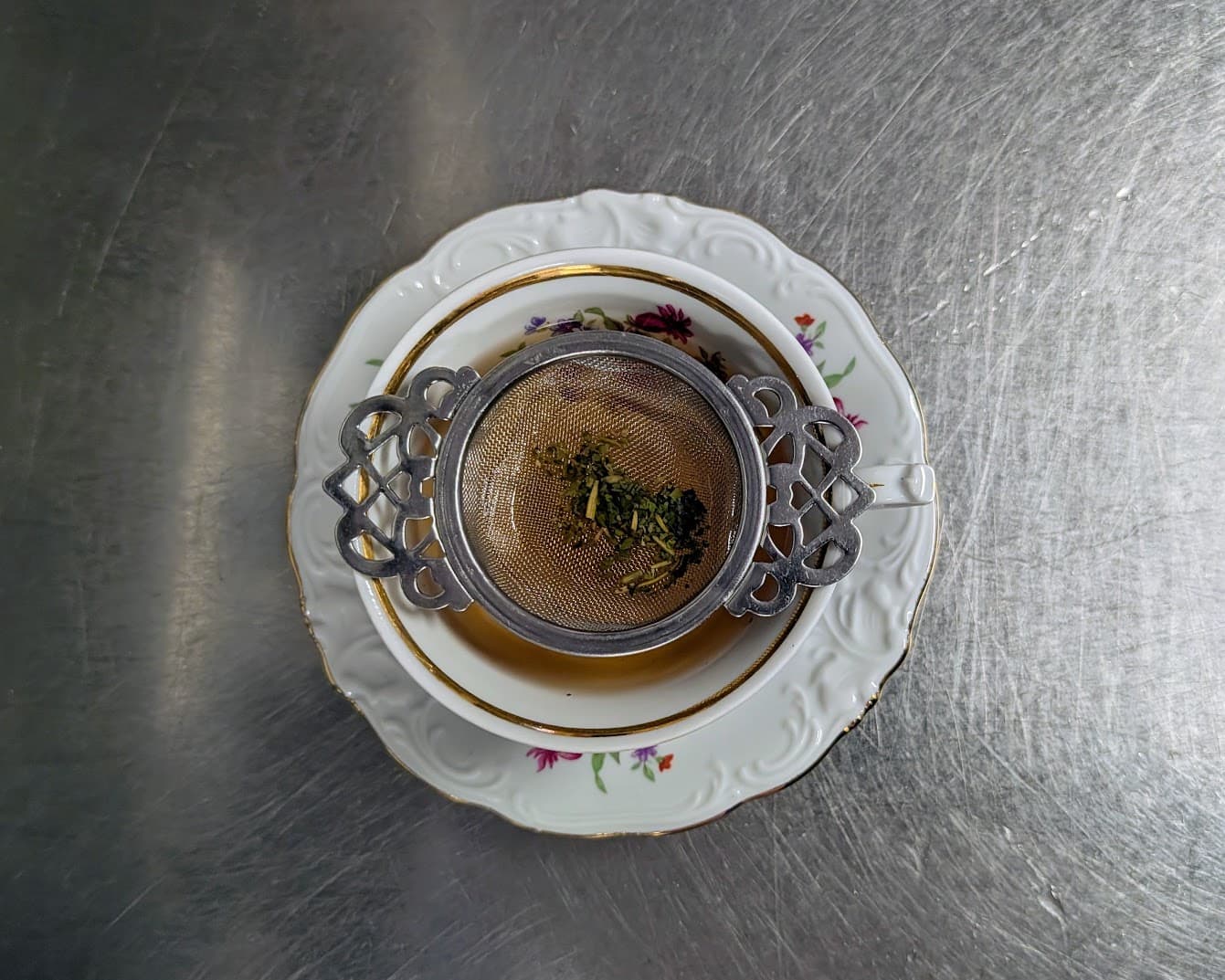 Tea infuser steeping loose leaf tea in a floral porcelain teacup